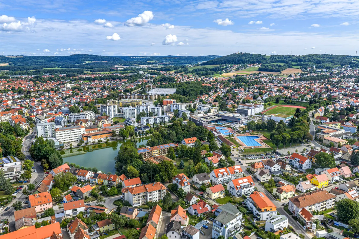 Luftaufnahme von Neumarkt i.d.OPf. mit Wohngebieten, Grünflächen und der Burgruine Wolfstein am Horizont.